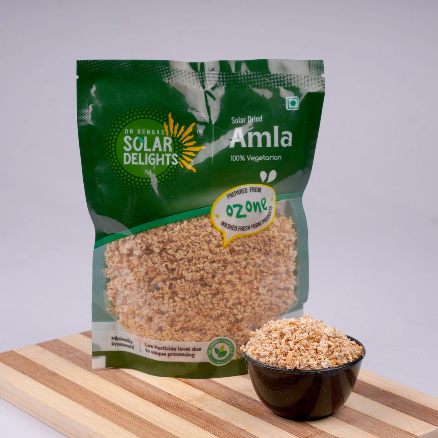 Fresh green amla fruits placed beside the packaged product