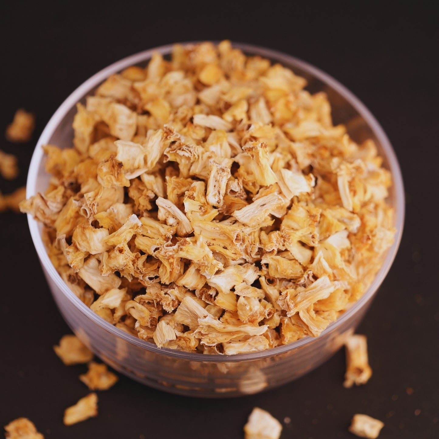 Dried pine apple  in a clear glass bowl on a dark background