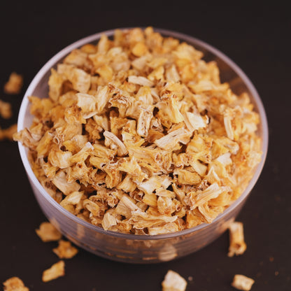 Dried pine apple  in a clear glass bowl on a dark background