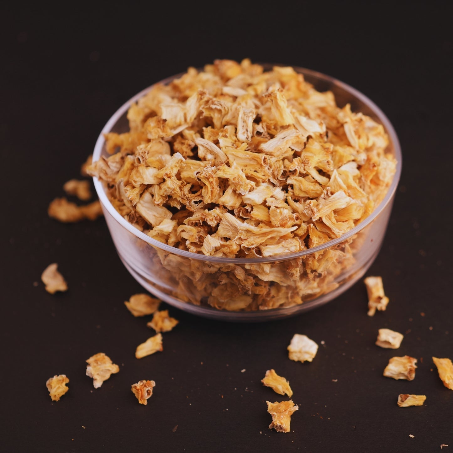 Clear bowl filled with dried pine apple  on a dark background