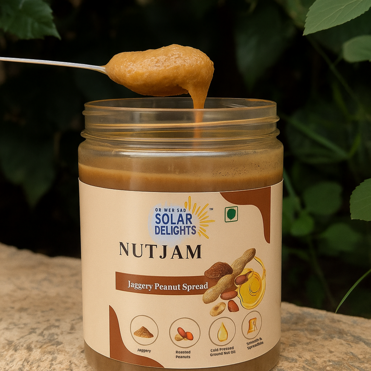 Jar of Solar Delights Nutjam with a spoonful of spread above it, against a natural background.